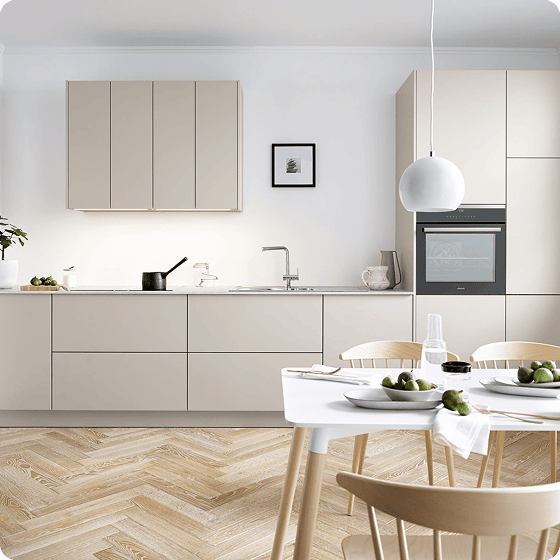 Moderne, helle Küche mit beige Möbeln, einem Esstisch und Stühlen, dekoriert mit Obstschalen und einer Pflanzen.